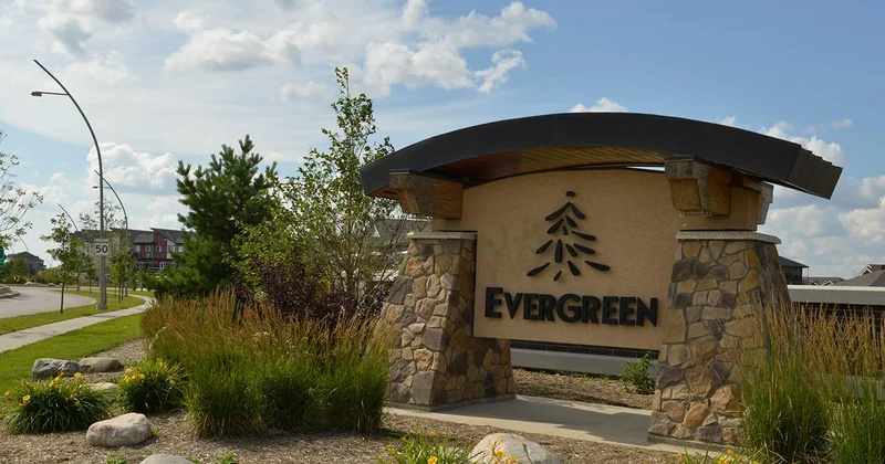 Evergreen neighbourhood entrance sign in Saskatoon on a summer day, stone pillars and landscaped beds