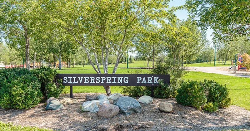 Silverspring Park sign in Saskatoon, surrounded by trees with a playground in the background