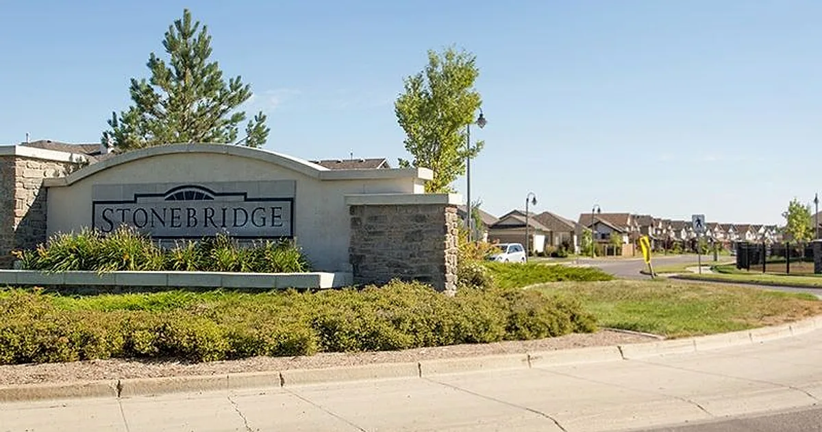 Stonebridge community entrance sign in Saskatoon, with homes along the street behind it